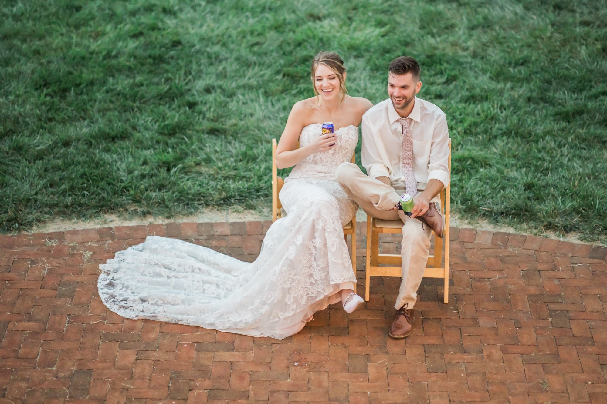 A couple with drinks in hand on the string-lit brick patio at golden hour.